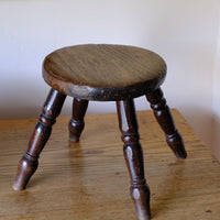 Antique English dairy milking stool with four turned legs and original dark painted finish