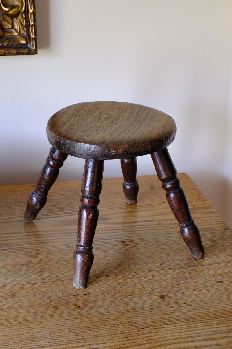 Antique English dairy milking stool with four turned legs and original dark painted finish