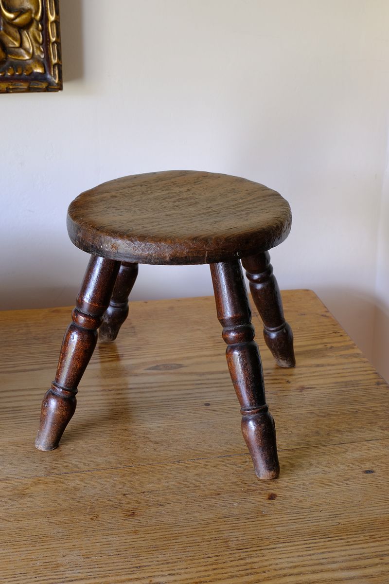 Antique English dairy milking stool with four turned legs and original dark painted finish