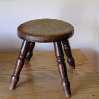 Antique English dairy milking stool with four turned legs and original dark painted finish