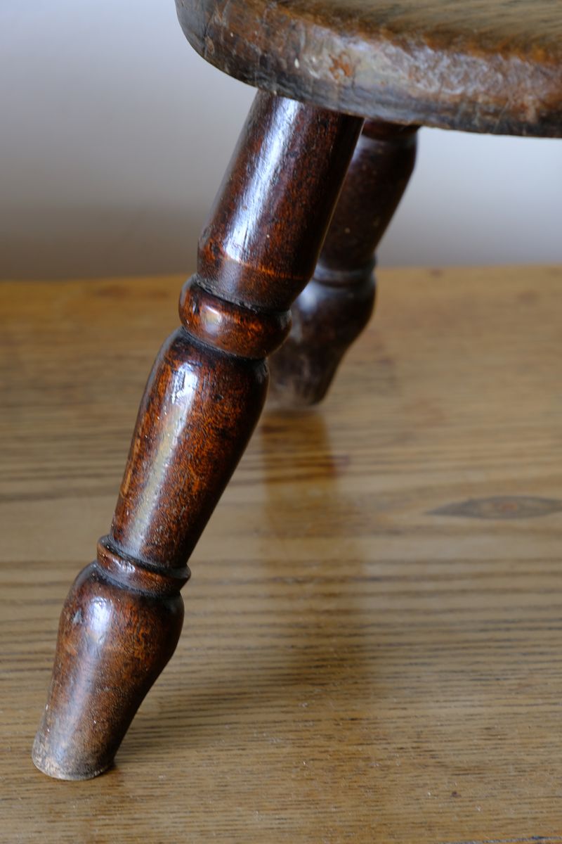 Antique English dairy milking stool with four turned legs and original dark painted finish