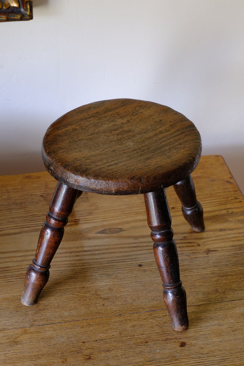 Antique English dairy milking stool with four turned legs and original dark painted finish