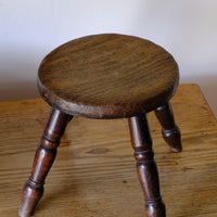 Antique English dairy milking stool with four turned legs and original dark painted finish