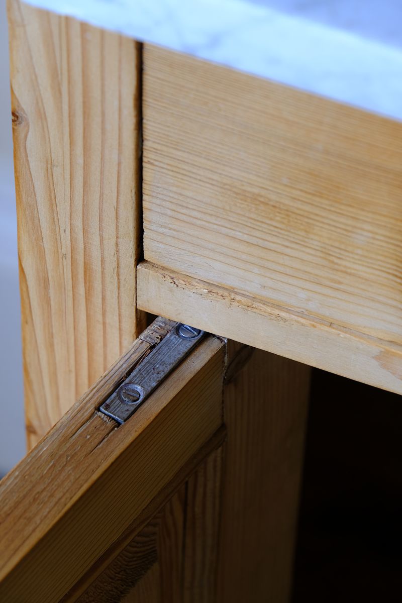 Close up of the original pivot hinge assembly on a Late Victorian pine marble top bedside cupboard with Carrara marble and concealed brass pivot hinges