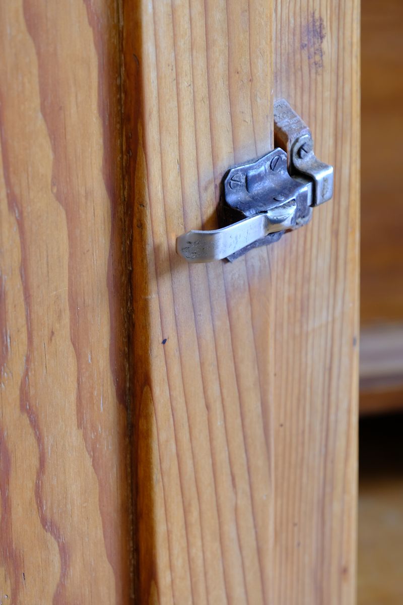Close up of the Original sprung steel refrigerator-style latch on an Early 20th Century Pitch Pine Single Door Larder Cupboard with Lift-Off Hinges and Original Sprung Latch