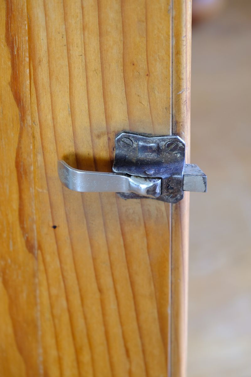 Close up of the Original sprung steel refrigerator-style latch on an Early 20th Century Pitch Pine Single Door Larder Cupboard with Lift-Off Hinges and Original Sprung Latch