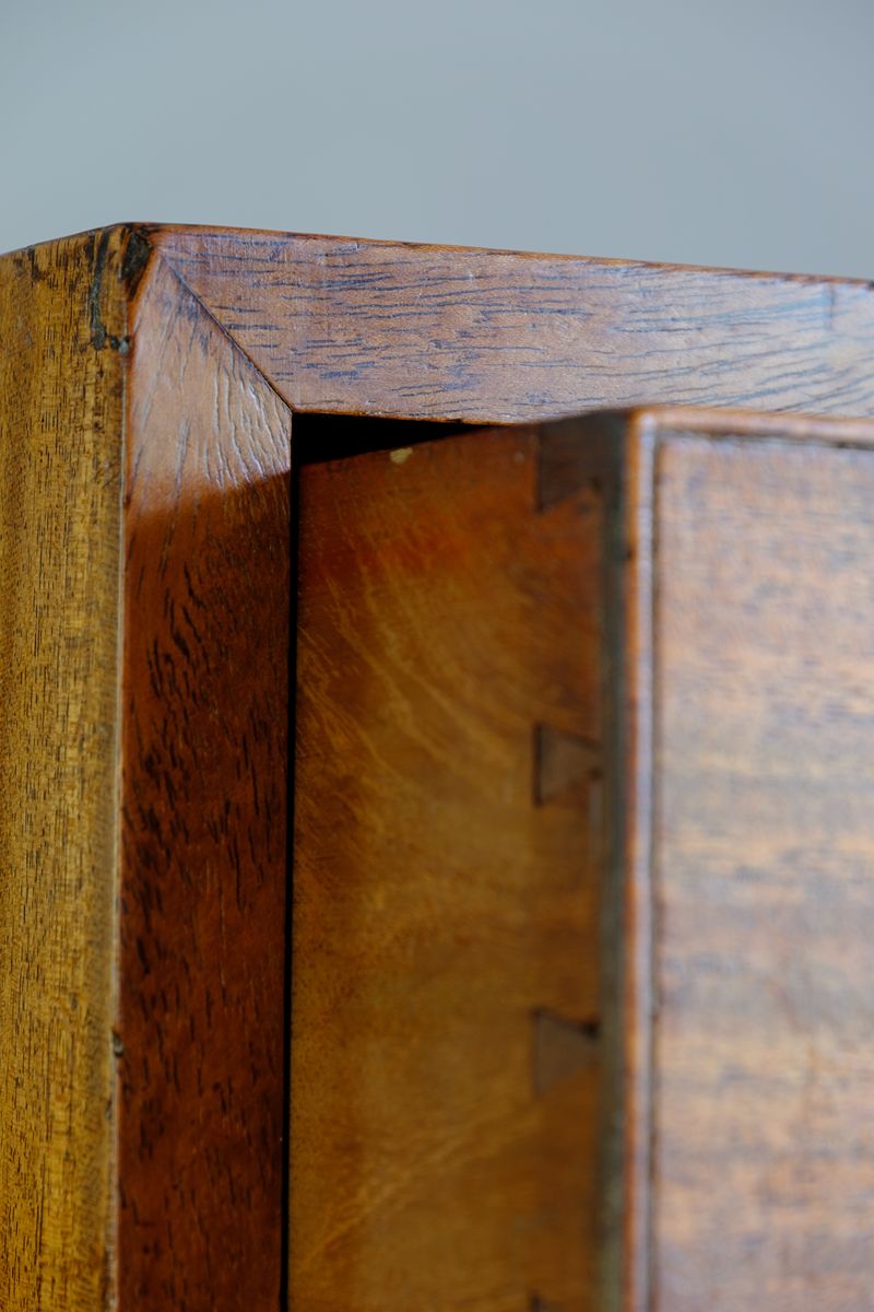 Close-up detail of a wooden cabinet corner showing the grain, finish, and internal dovetail joint construction. Late Georgian Anglo-Chinese Padauk Chest of Drawers with Mitred Face Frame and Original Brass Side Carrying Handles