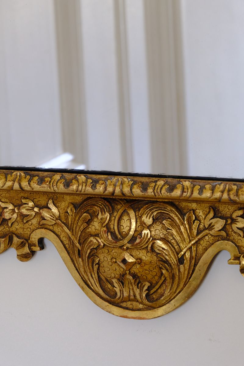 close up of A richly carved lower apron with flowing foliate scrollwork centred by a faceted diamond motif. Edwardian Queen Anne Revival carved giltwood wall mirror with Prince of Wales feather crest, c.1900