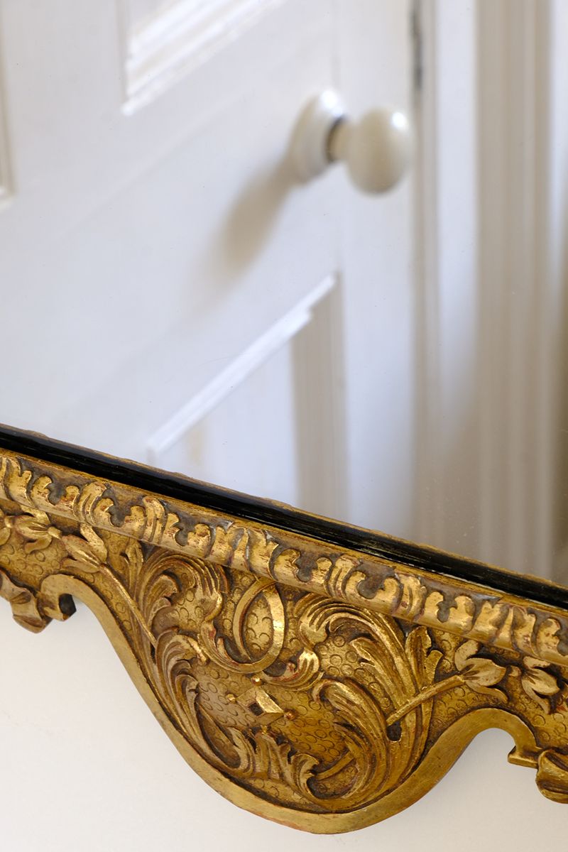 A richly carved lower apron with flowing foliate scrollwork centred by a faceted diamond motif on an Edwardian Queen Anne Revival carved giltwood wall mirror with Prince of Wales feather crest, c.1900-  