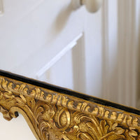 A richly carved lower apron with flowing foliate scrollwork centred by a faceted diamond motif on an Edwardian Queen Anne Revival carved giltwood wall mirror with Prince of Wales feather crest, c.1900-  