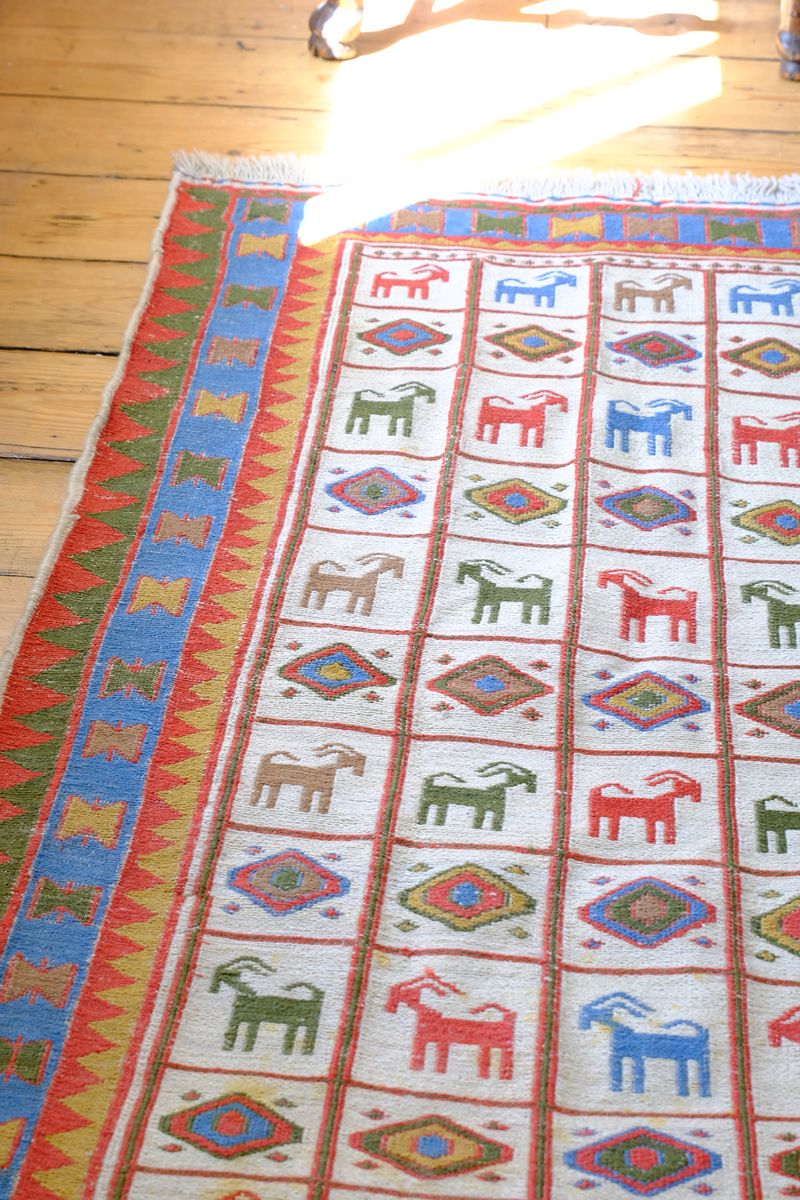 Handwoven Persian Sumak rug featuring colourful stylised goat motifs and geometric borders
