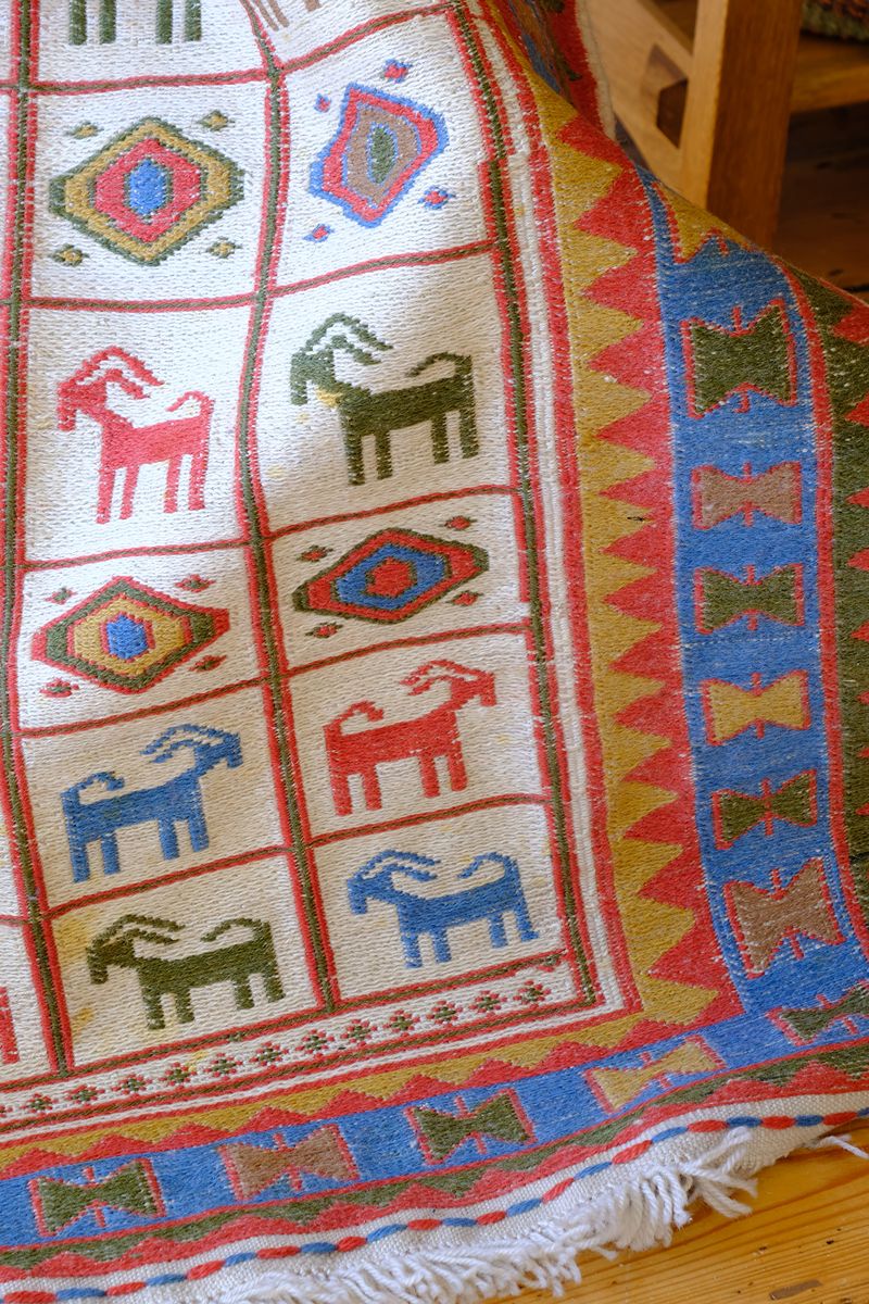 close up of a Traditional Persian Sumak wool flatweave rug with repeating goat motifs and geometric design