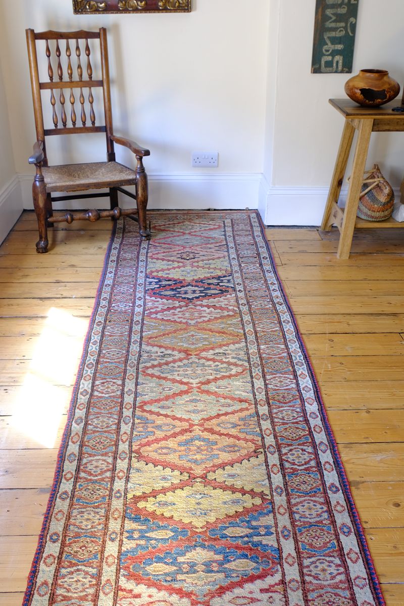 Different light shining on the Mid-20th Century North-West Persian ivory ground hand-knotted wool runner with fourteen hooked lozenge medallions