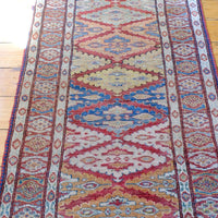Harmony of colours throughout the Mid-20th Century North-West Persian ivory ground hand-knotted wool runner with fourteen hooked lozenge medallions