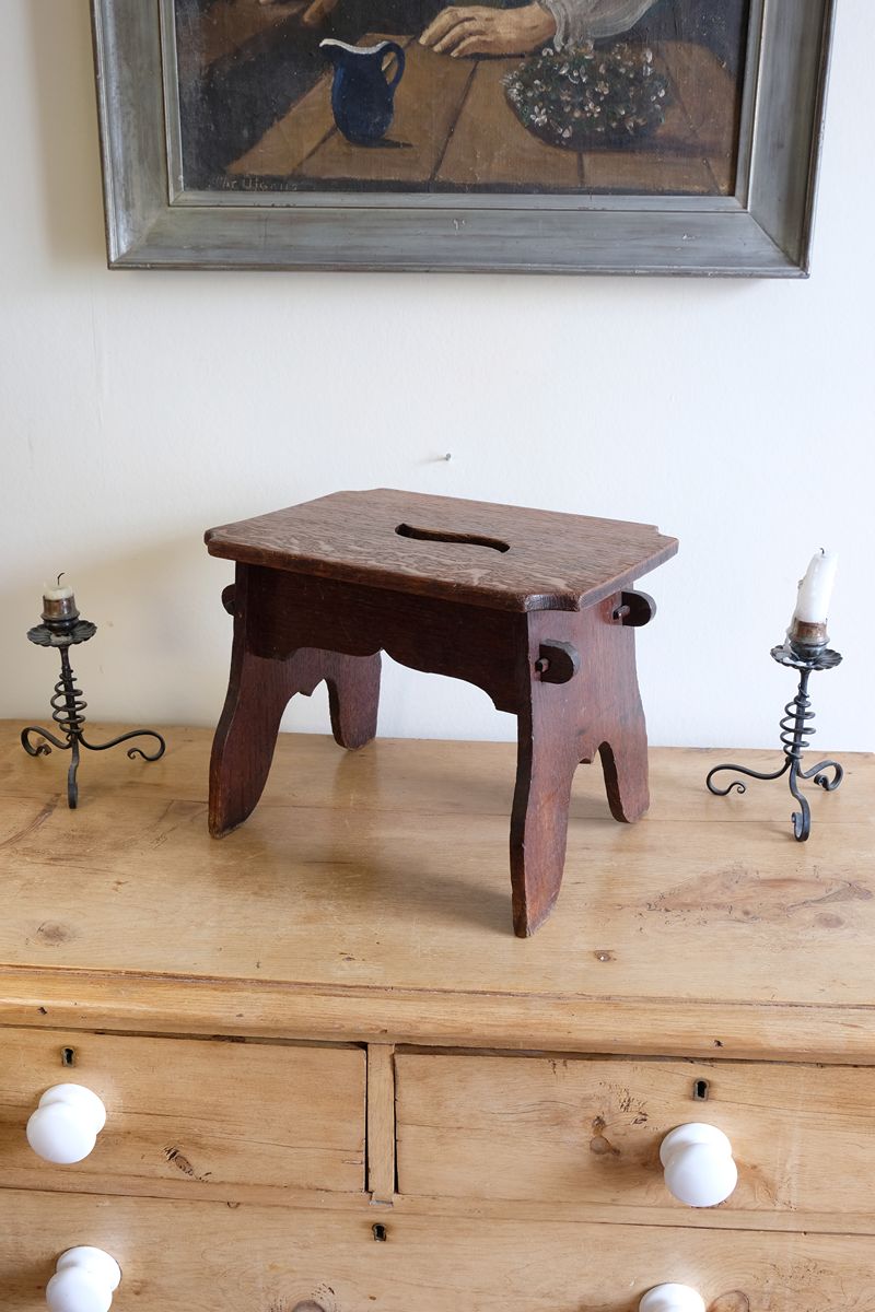 Antique Arts and Crafts oak low stool with S-shaped carrying handle, fret-cut arches and exposed keyed through-tenons, circa 1900.