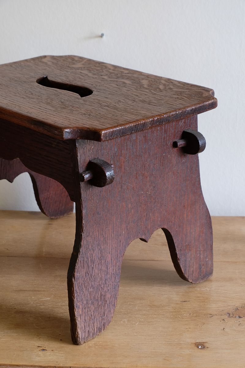 Antique Arts and Crafts oak low stool with S-shaped carrying handle, fret-cut arches and exposed keyed through-tenons, circa 1900.