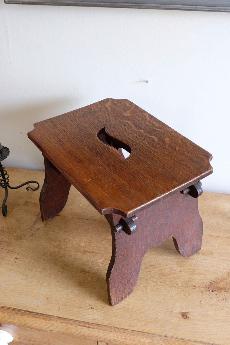 Top of the stool  highlighting the concave corner detailing on this Antique Arts and Crafts oak low stool with S-shaped carrying handle, fret-cut arches and exposed keyed through-tenons, circa 1900.