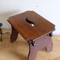 Top of the stool  highlighting the concave corner detailing on this Antique Arts and Crafts oak low stool with S-shaped carrying handle, fret-cut arches and exposed keyed through-tenons, circa 1900.