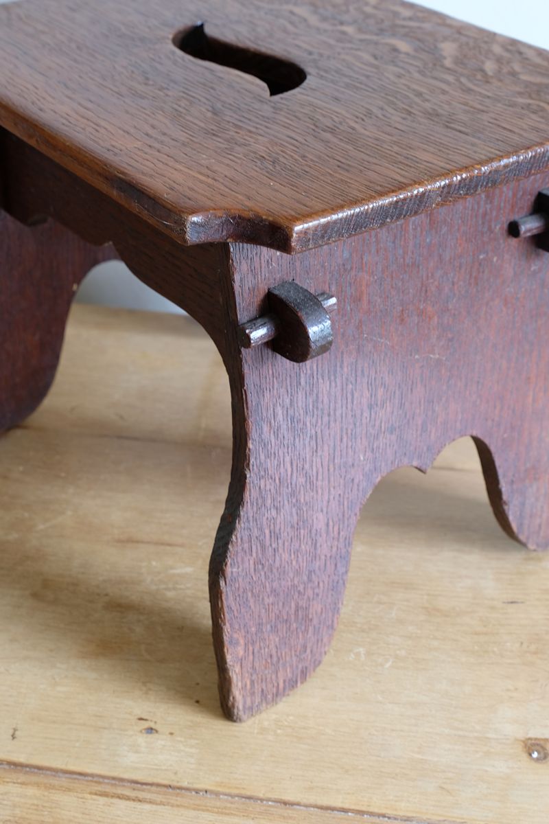 Antique Arts and Crafts oak low stool with S-shaped carrying handle, fret-cut arches and exposed keyed through-tenons, circa 1900.