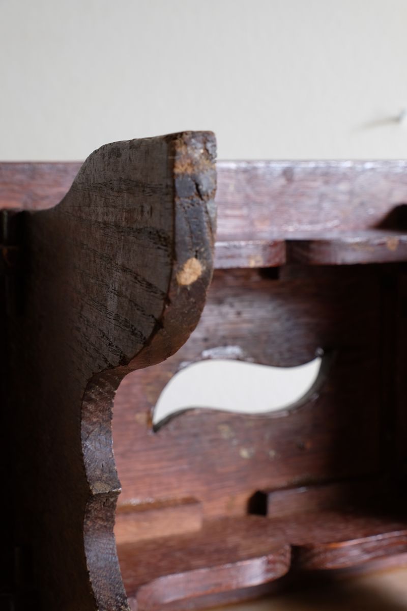 Wear on the underside of the leg of the Antique Arts and Crafts oak low stool with S-shaped carrying handle, fret-cut arches and exposed keyed through-tenons, circa 1900.