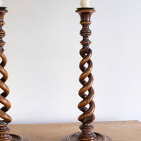 Pair of tall antique oak open barley twist candlesticks with original brass sconces and weighted circular bases