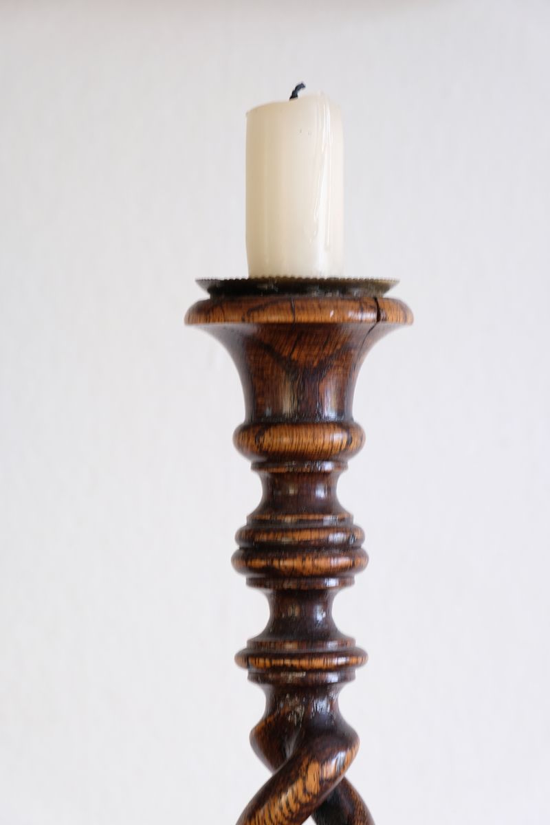 Sconce detail on a Pair of tall antique oak open barley twist candlesticks with original brass sconces and weighted circular bases