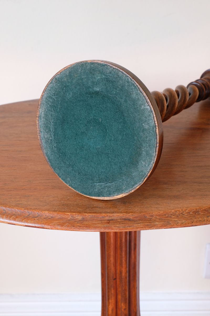 Worn green baize beneath the weighted base of an antique oak candlestick