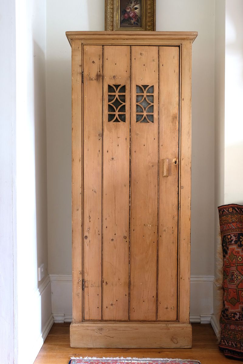 Antique pine cupboard, circa 1890–1910, with a boarded door, two pierced ventilation panels and a plinth base