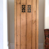 Antique pine cupboard, circa 1890–1910, with a boarded door, two pierced ventilation panels and a plinth base
