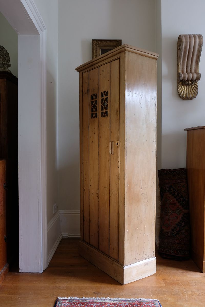 Antique pine cupboard, circa 1890–1910, with a boarded door, two pierced ventilation panels and a plinth base