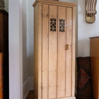 Antique pine cupboard, circa 1890–1910, with a boarded door, two pierced ventilation panels and a plinth base