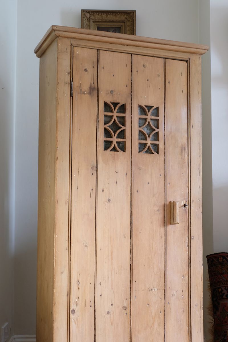 Antique pine cupboard, circa 1890–1910, with a boarded door, two pierced ventilation panels and a plinth base