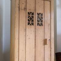 Antique pine cupboard, circa 1890–1910, with a boarded door, two pierced ventilation panels and a plinth base