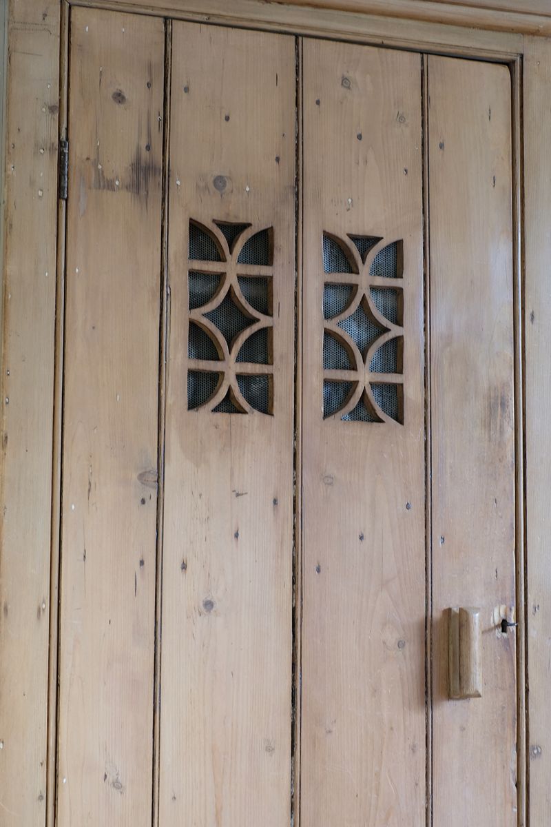 Antique pine cupboard, circa 1890–1910, with a boarded door, two pierced ventilation panels and a plinth base