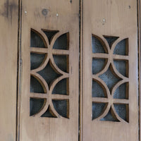 close up of the fret work tracery on the Antique pine cupboard, circa 1890–1910, with a boarded door, two pierced ventilation panels and a plinth base