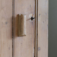 close up of the shaped wooden handle - Antique pine cupboard, circa 1890–1910, with a boarded door, two pierced ventilation panels and a plinth base