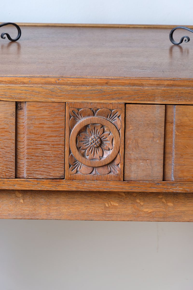 Close up of the carved Yorkshire Rose on a Arts & Crafts oak console table by Beresford & Hicks with two drawers and shaped trestle supports