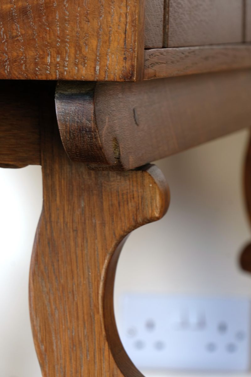 Scrol end frame supports on the Arts & Crafts oak console table by Beresford & Hicks with two drawers and shaped trestle supports