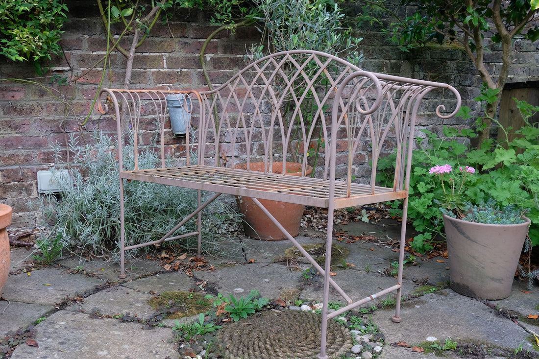 Painted wrought iron garden bench with Gothic arch back, scroll armrests and slatted seat