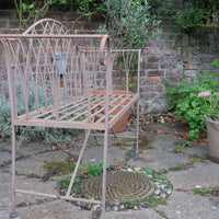Painted wrought iron garden bench with Gothic arch back, scroll armrests and slatted seat