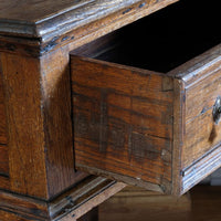 Close up of the hand cut dovetail joints on the 18th century country oak side table with a single panelled drawer, brass handles and baluster-turned front legs