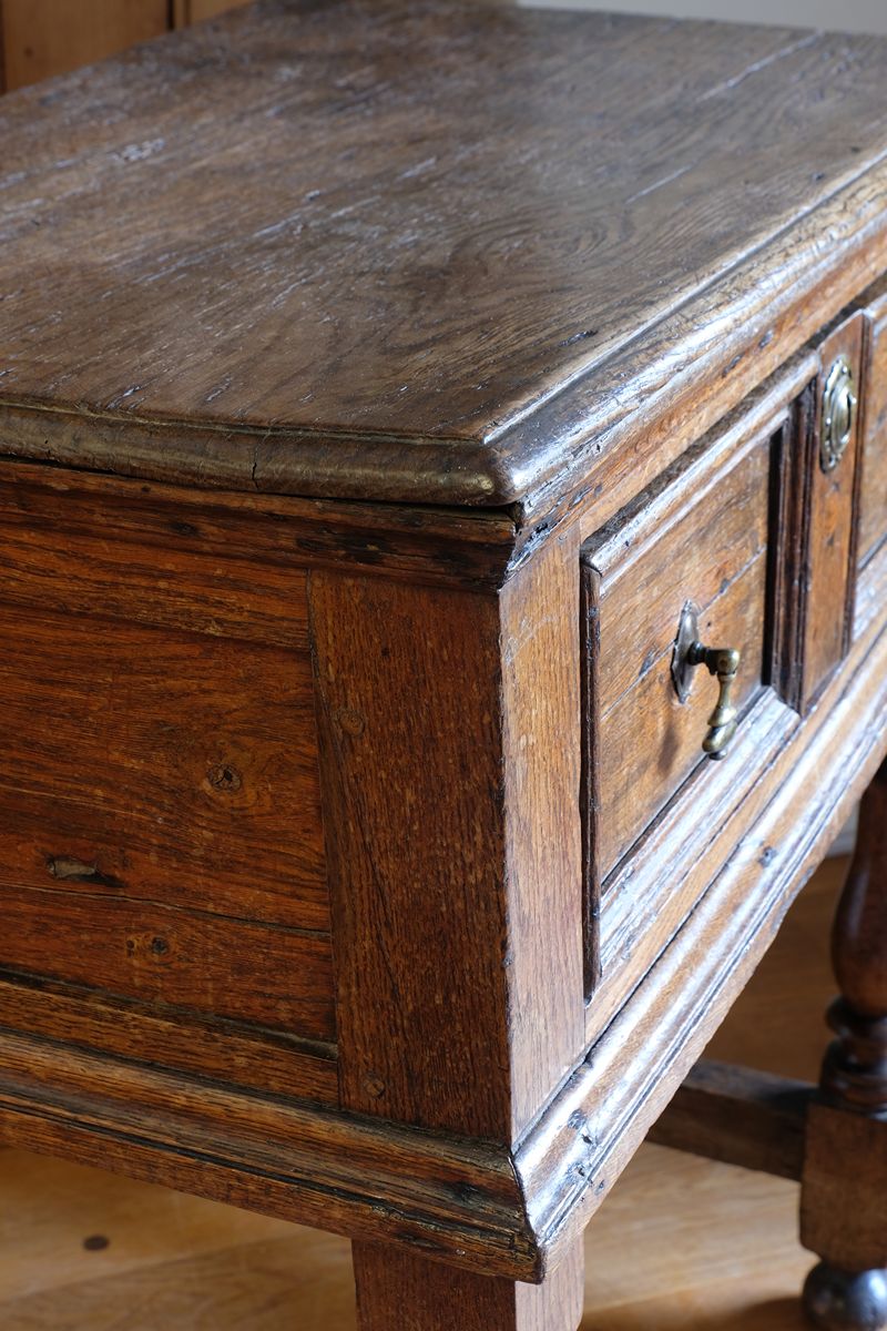 18th century country oak side table with a single panelled drawer, brass handles and baluster-turned front legs